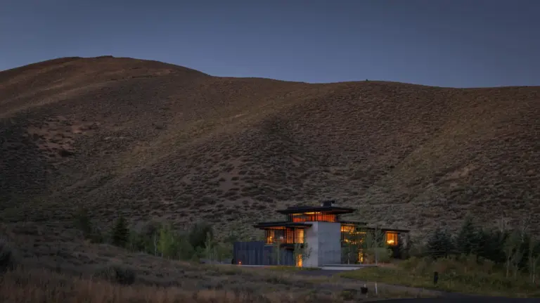 Sky View Residence di Olson Kundig al crepuscolo, vista d'insieme tra le colline di Sun Valley, Idaho