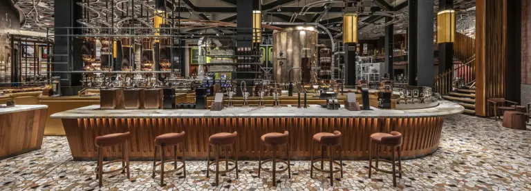 Il bancone bar in marmo Calacatta con le tubature in rame sospese sopra la pavimentazione a graniglia, Starbucks Reserve Roastery di Milano