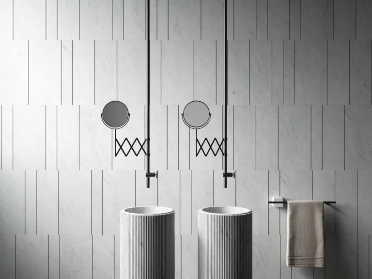 Bagno rivestito con il sistema Tratti di Elisa Ossino per Salvatori, lastre in Bianco Carrara scandite da bacchette metalliche nere